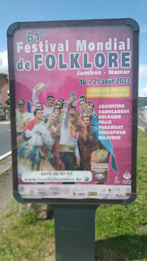 Photo prise au bord de la Meuse, début août 2023, d’une affiche pour le « Festival du folklore » à Namur et Jambes. Sur l’affiche, des personnes, toutes habillées de différents costumes traditionnels, se regroupent pour prendre un selfie.
