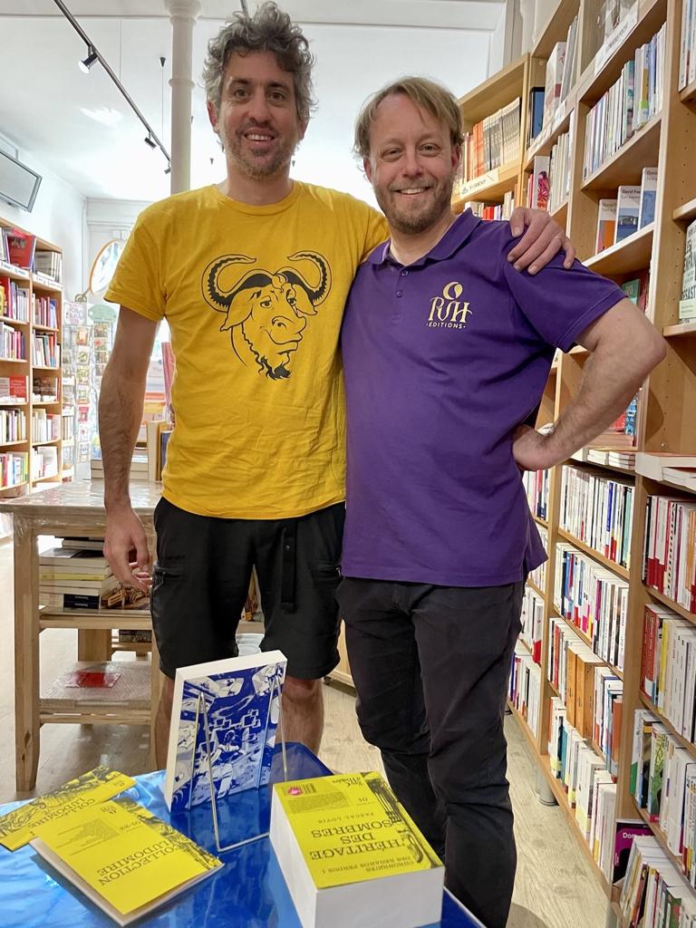 GNU/PVH, Ploum et Lionel dans une librairie, avec t-shirt GNU jaune et un polo mauve PVH